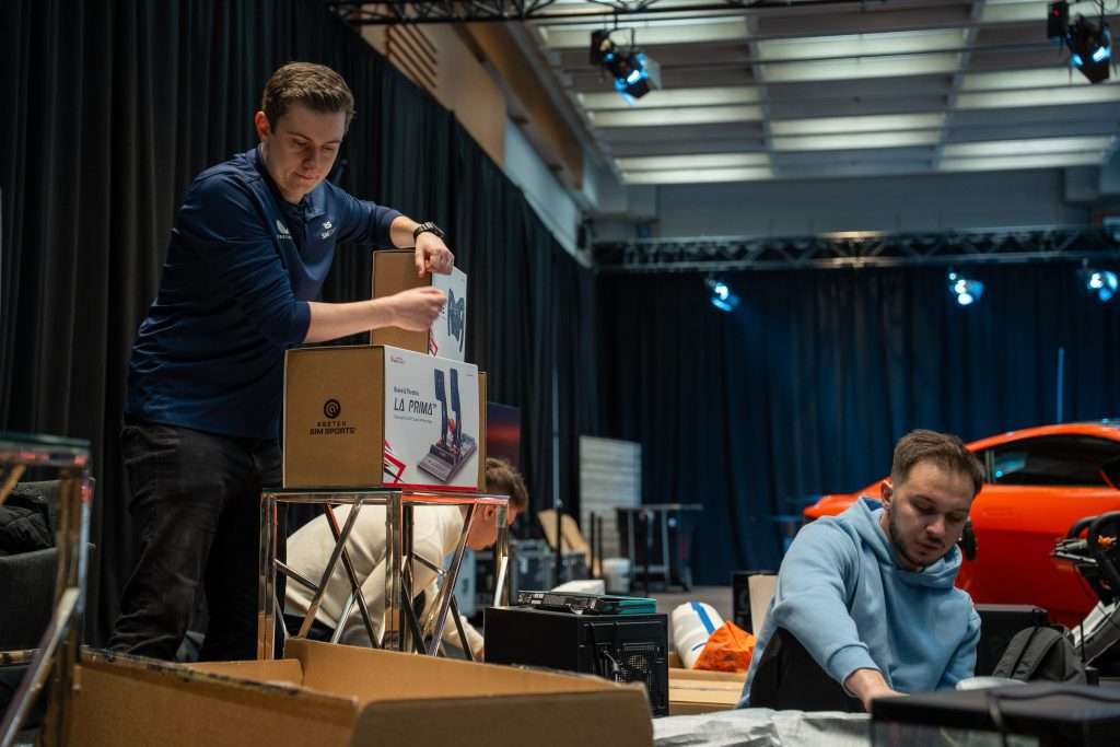 Two people setting up a racing simulator at an event.